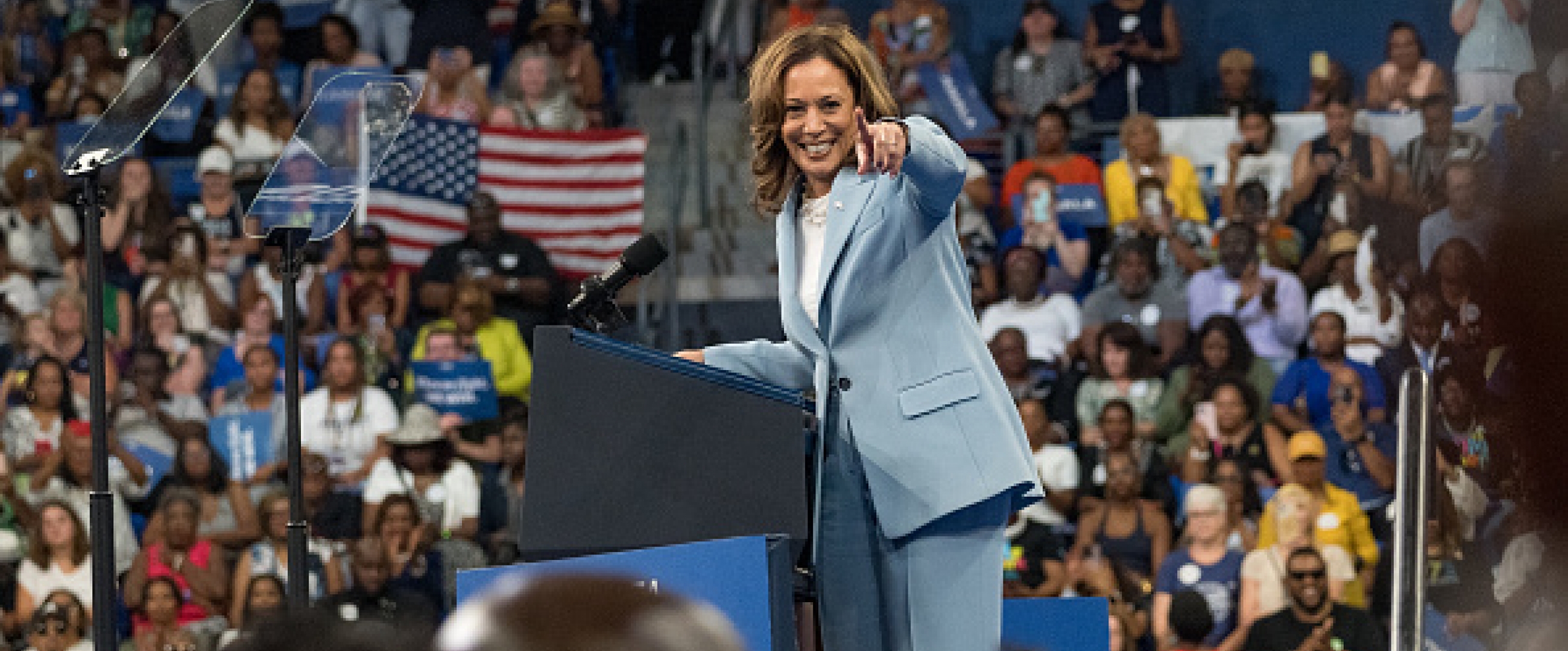 Wearing a powder blue suit, a grinning Vice President Kamala Harris points happily at a supporter during her July 30th rally in Atlanta 