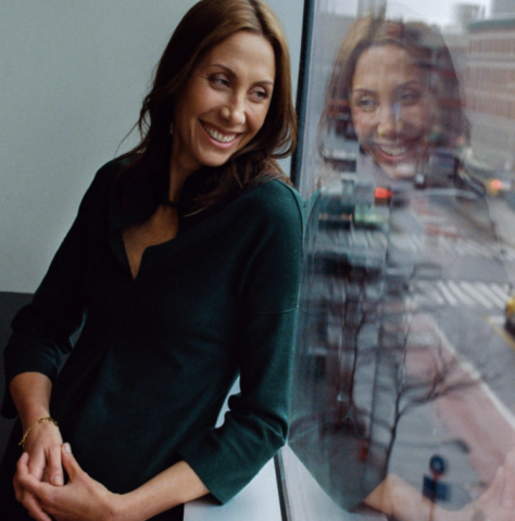 Attorney Jen DaSilva gazes, smiling, out a window in an urban environment. 